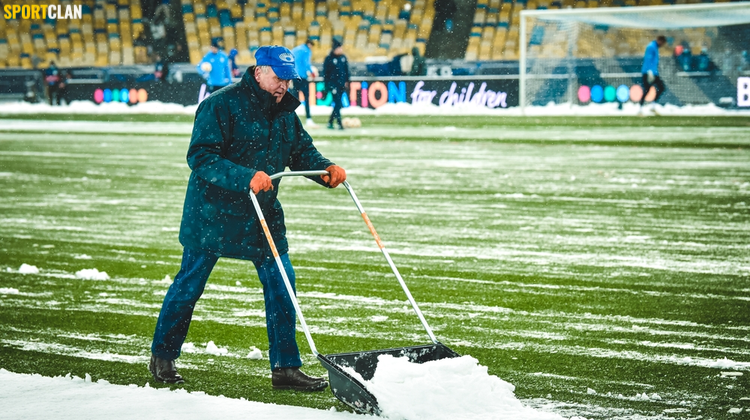убирает снег с футбольного газона