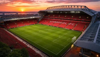Anfield Stadium at sunset with red seats and a green soccer pitch, home of Liverpool FC.