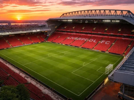 Anfield Stadium at sunset with red seats and a green soccer pitch, home of Liverpool FC.
